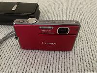 Red Panasonic Lumix DMC-FP1 facing front showing lens and flash.