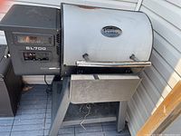 Left-side view showing pellet hopper, digital control panel marked SL700, cooking chamber and side shelf