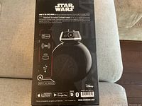 Back side of box showing features like 60+ min charge, 30m range, app compatibility, and charging icons.