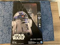Front of the box showing Star Wars Smart R2-D2 with partial window revealing the robot inside. Includes logos and size/age info.
