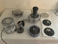 Full set with Veggie Bullet motor base, clear food processing bowl, multiple discs (slice, dice, spiralize), and pusher tool arranged on a table.