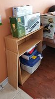 Photo of small wooden bookcase with adjustable shelf, showing contents on and inside the shelf (contents not included).
