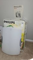 White Philips HF3301 bright light therapy lamp with original packaging and manual on carpeted floor.