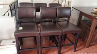 Set of six dining chairs with dark brown padded seats and backs in a group photo.