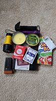 Photo of all items: playing cards, Skip-Bo, travel backgammon case, citronella candles, flashlights arranged on carpet