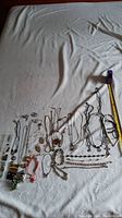 Photo of multiple necklaces, bracelets, and earrings displayed on white fabric with measuring tape for scale