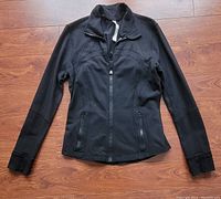 Front view of black Lululemon Defined Jacket showing zipper, thumbholes, front pocket, and general condition.