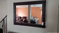 Full view of the rectangular plastic framed mirror hanging on a wall reflecting a room interior.
