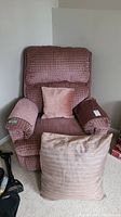 Full view of the fabric covered rocker recliner chair with small throw pillow and two arm protectors in dusty rose fabric.