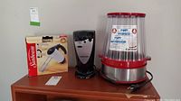 Sunbeam hand mixer with box, Black & Decker electric can opener, and Cuisinart popcorn popper on a table