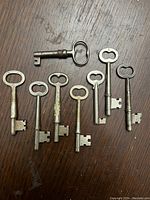 All eight antique metal keys laid out on a wood surface with visible wear and patina on the keys.