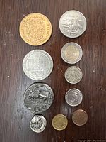 Top-down photo showing all ten coins and tokens arranged in two columns on a wooden surface.
