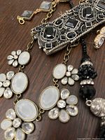 Close-up detail of faux moonstone floral necklace and black crystal beaded necklace with matching earrings.