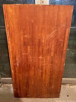 Front side of butcher block slab showing darker finish wood surface with wear and scratches.