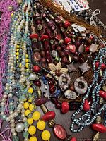 Various beaded necklaces laid flat showing different colors, bead types, and styles including natural stone, glass, acrylic, and seed beads.