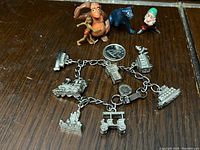 Photo of tiny plastic figures King Louie, Bagheera, Mowgli, and 7 Dwarves figure with a dime for size reference.