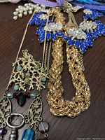 Gold tone braided necklace with blue and purple crystal floral necklace and coral reef pendant