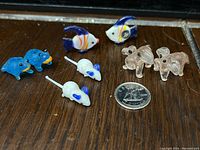 All eight miniature glass animal figurines shown with a dime for size reference on a wood surface.