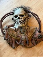 Front view of latex mask and chest armor laid flat showing tubes, gears and paint finish