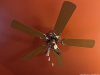 Photo showing five wood blades with metal finish hub and three atomic-style light fixtures, pull chains visible.