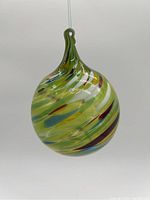 Front view of the hand blown glass bauble showing swirl pattern and shape.