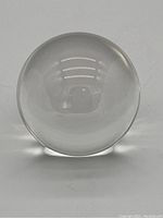 Front view of the crystal ball showing clear surface, reflection of lighting, slight surface chips and imperfections.