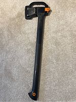 Full view of Fiskars ax with black handle and protective guard over blade, showing the entire length and handle shape.