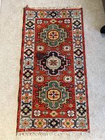 Full view of handknotted rug showing overall design and condition with fringe edges visible