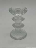 Photo of single clear glass Iittala Festivo candleholder with textured finish and decorative rings on stem.