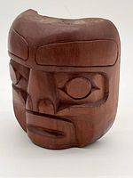 Front angled view showing detailed carving of facial features on cedar mask.