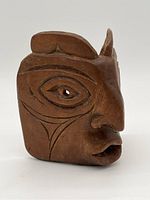 Side angle view of the carved wooden mask showing profile with raised nose, lips, and tribal cheek carvings.