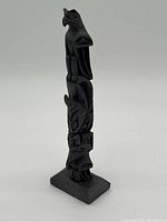 Full view of the carved native totem pole showing all four animal figures stacked vertically on a rectangular base.