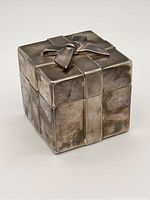 Silver plate square gift box with bow design shown from angled front left side, exhibiting tarnish and surface wear.