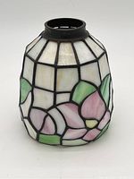 Stained glass lamp shade viewed at an angle showing floral pattern and metal top.