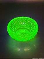 Uranium glass bowl glowing bright green under UV light, showing exterior pattern and rim details