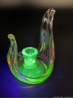 Candleholder glowing bright green under UV light, showing the distinctive fluorescence of uranium glass.