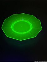 Uranium glass plate glowing bright green under UV light, showing its fluorescent properties.