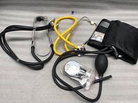 Two stethoscopes and manual blood pressure tester shown together on surface.