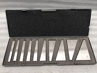 Photo of 10 metal angle blocks arranged in foam-lined plastic case from smallest to largest with angles engraved on each.