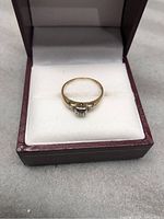 Ring displayed in a maroon box with white cushion, showcasing the front view of the ring.