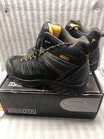 Pair of black and yellow Dakota Rabin mid cut hiker boots on top of Dakota branded box, showing side view