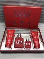 Four items inside clear plastic insert showing two fragrance bottles and two after shave balm tubes, all red with silver or white accents.