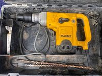 Full view of the DEWALT D25500 rotary hammer drill placed in its black plastic case along with two drill bits and power cord.