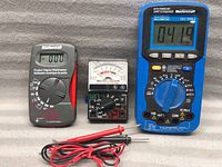 Three Mastercraft multimeter testers shown together: two pocket digital multimeters and one blue analog multimeter with test probes.