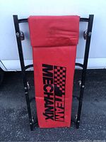 Top view of the red padded mechanic creeper showing 'Team Mechanix' logo and checkered flag design.