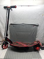 Full side view of Razor E90 electric scooter showing handlebar, deck with graphics, front wheel, and rear motorized wheel.