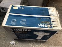 Photo of the boxed Rona pedestal sink with product details and measurements visible on the box.