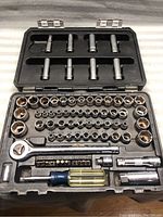 Top view of socket set showing ratchet, sockets, driver with blue handle, and metal extensions in a plastic molded case