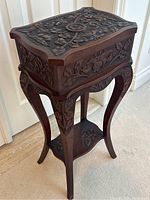 Angled view of entire pedestal table showing carved top, sides, legs and lower shelf