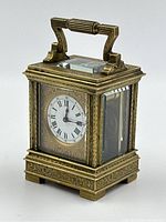 Three-quarter front view showing handle, engraved brass case, front and side glass panels